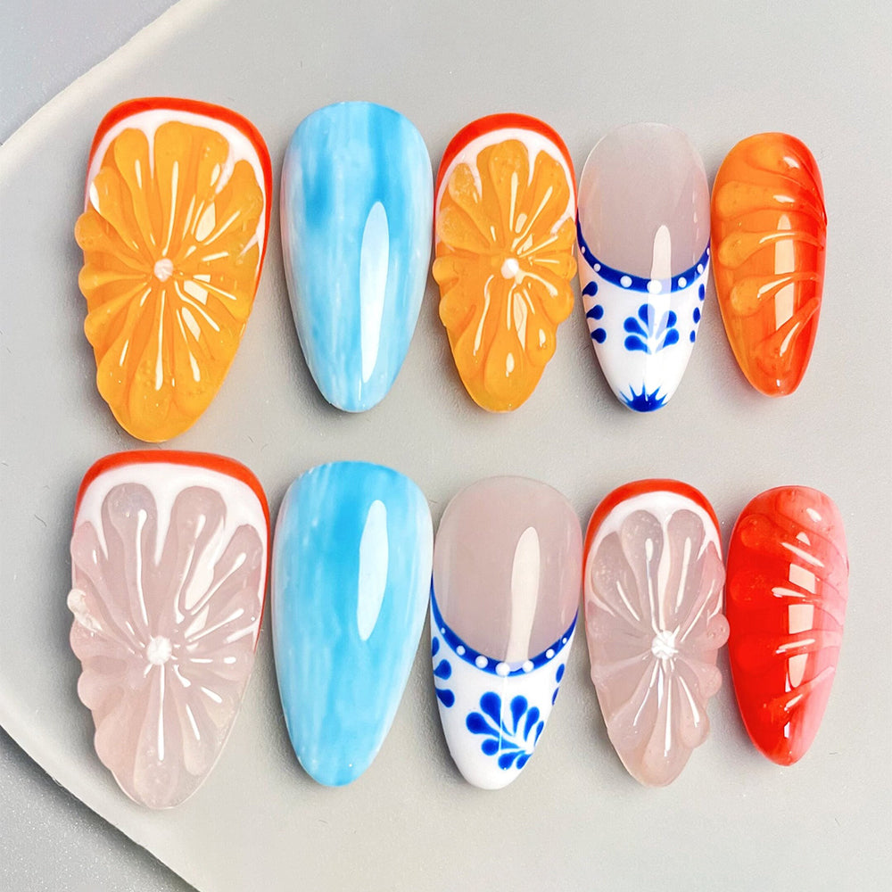 Ten press-on nails with orange slices, blue strokes and white floral details